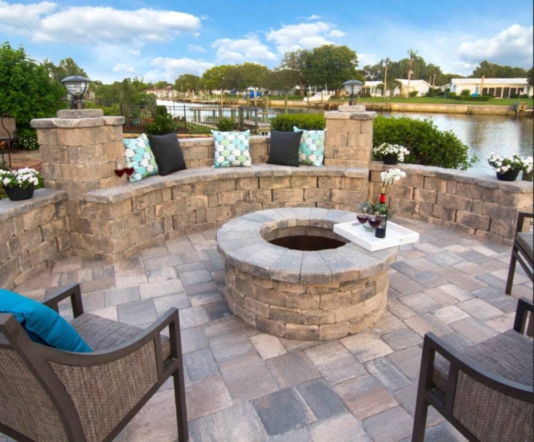 Circular stone fire pit ringed by a low paver seat wall in a Freeport back yard