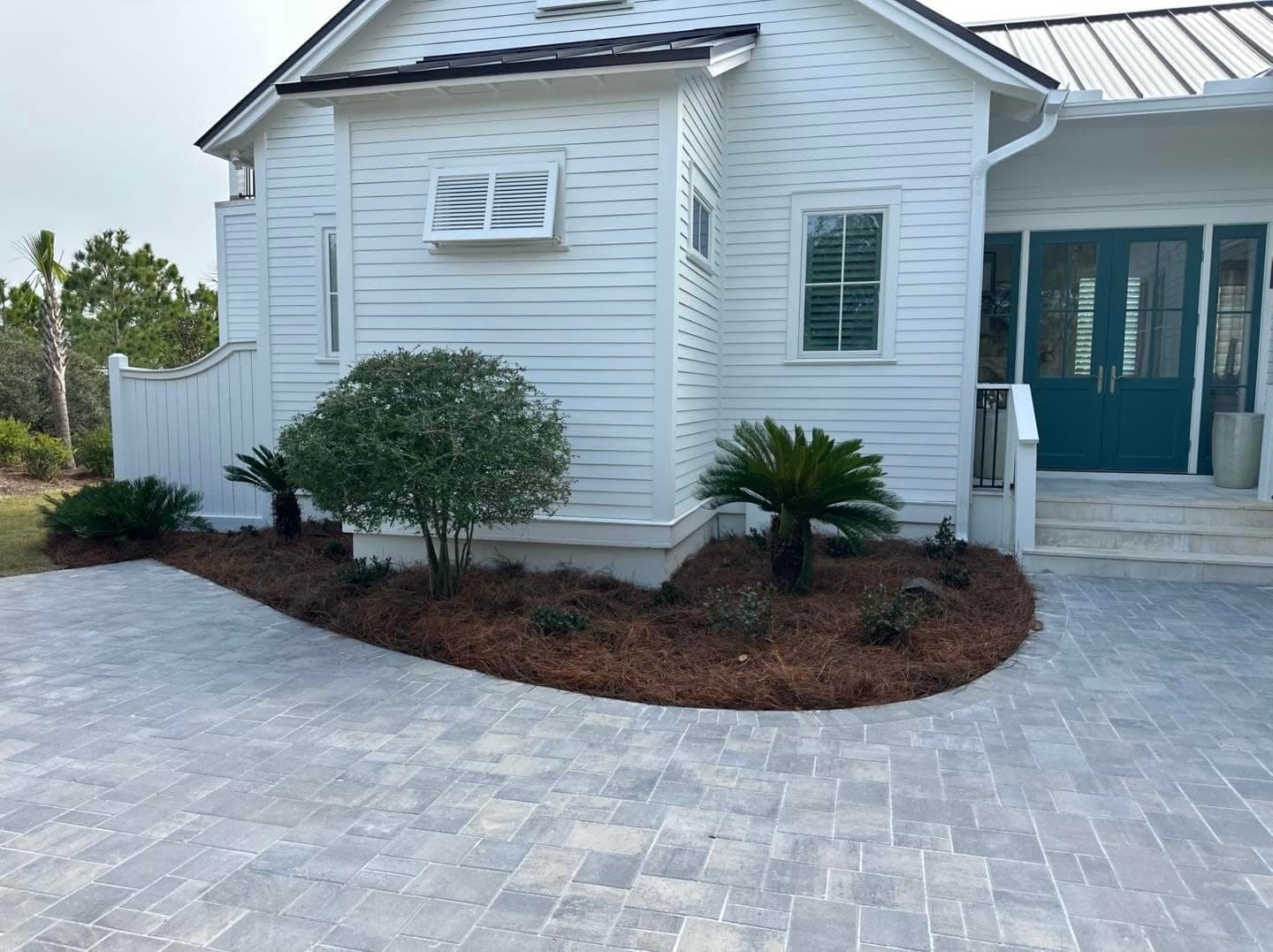 Gray brick paver driveway with a darker soldier-course border at a white coastal home in Santa Rosa Beach