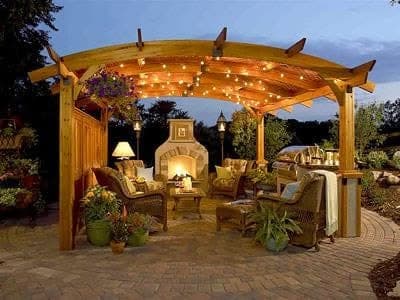 Stone-columned pergola over a paver sitting area at a Santa Rosa Beach home, lit from below at dusk