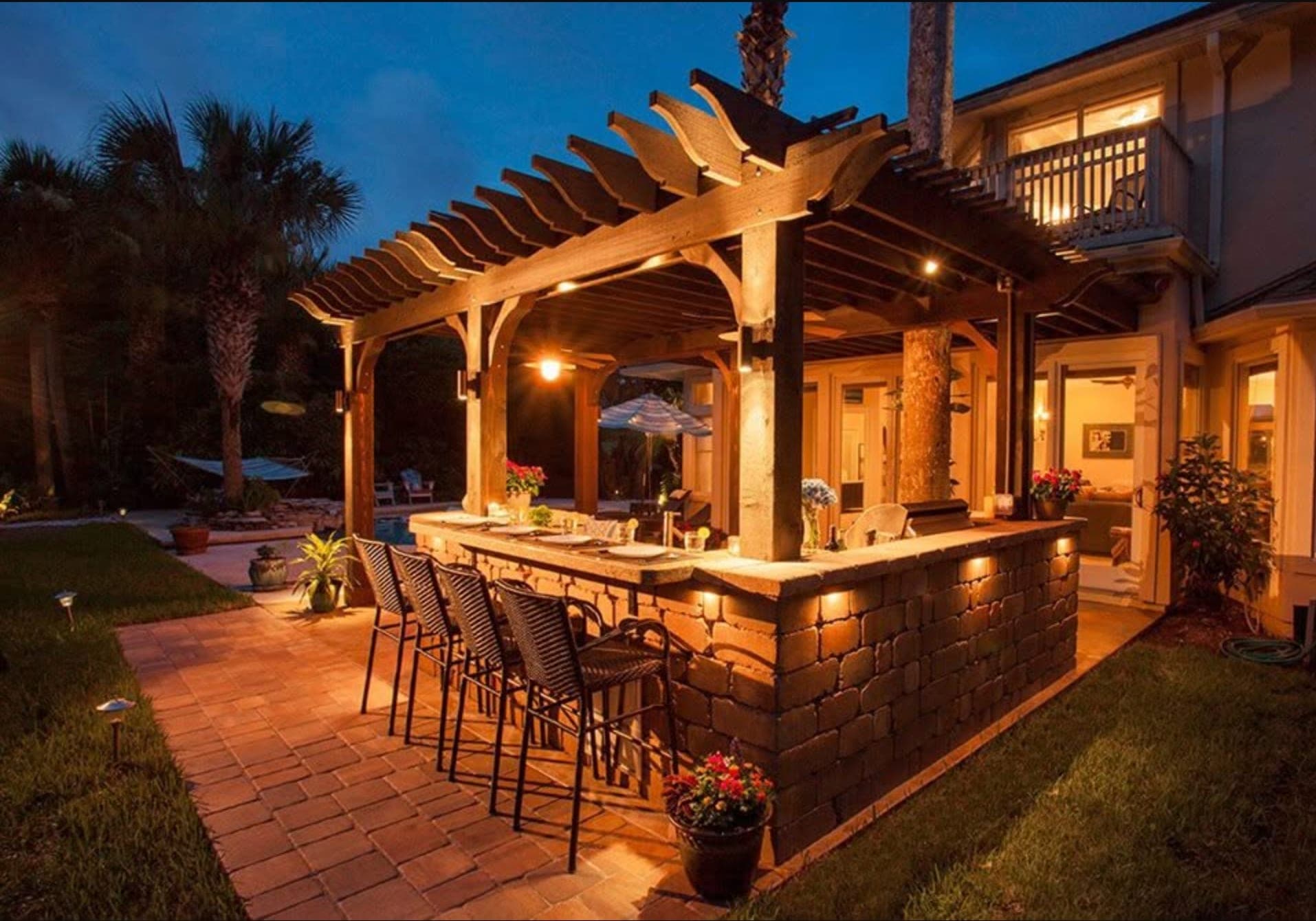 Lit pergola and outdoor kitchen at twilight